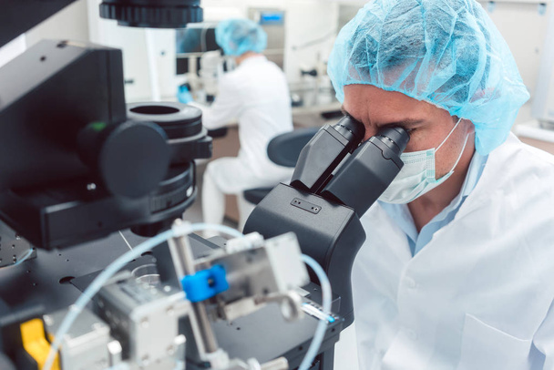 Lekarz lub naukowiec patrzący przez mikroskop w laboratorium - Zdjęcie, obraz