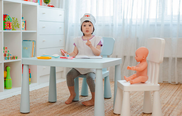 Bambina 3 anni in età prescolare giocare medico con la bambola. Il bambino fa un giocattolo per iniezione
. - Foto, immagini