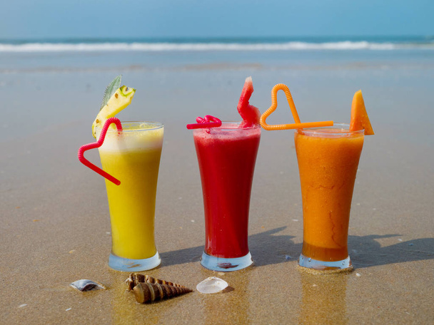 Három pohár természetes gyümölcslé tubulusok a tengerparton - Fotó, kép