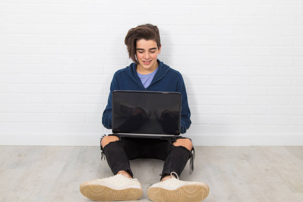 Genç adam dizüstü bilgisayarla yerde oturuyor. - Fotoğraf, Görsel