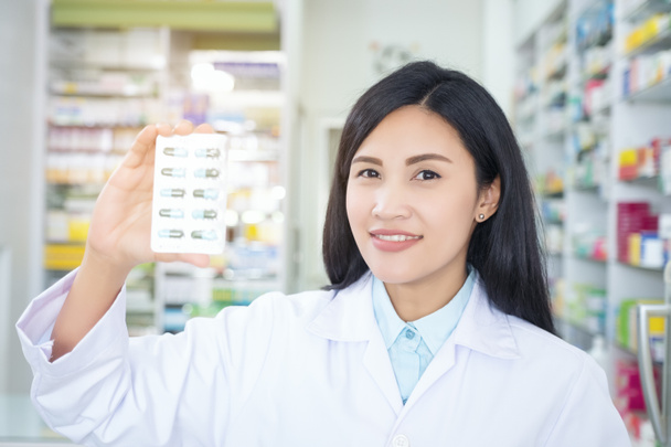 Pharmacist holds a packet of pills in her hands. Then she shows  - Foto, imagen