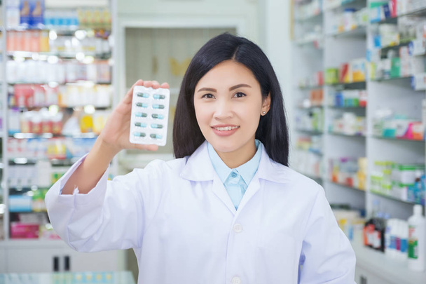 Pharmacist holds a packet of pills in her hands. Then she shows  - Foto, imagen
