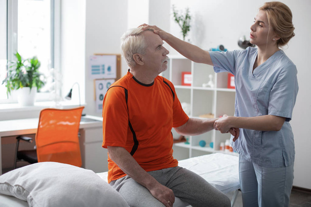 Nice sympathetic nurse touching her patients head - Photo, image