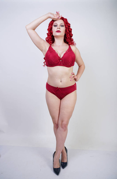 sexy kurvige Mädchen mit roten lockigen Haaren trägt Spitze sexy Dessous und High Heels im Studio - Foto, Bild