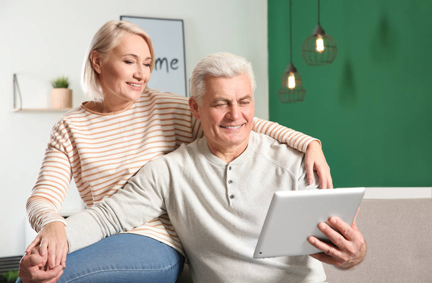 Mature couple using video chat on tablet at home - Photo, image