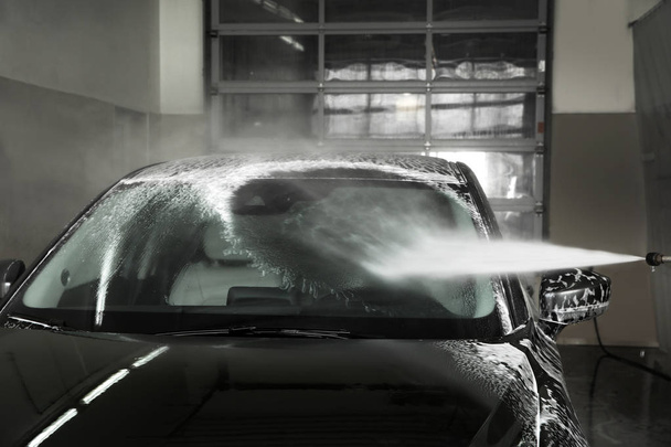 Cleaning automobile with high pressure water jet at car wash - Foto, Imagen