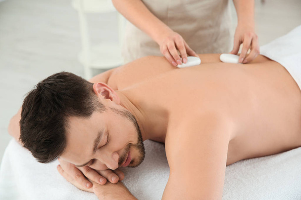 Handsome man receiving hot stone massage in spa salon - Photo, Image