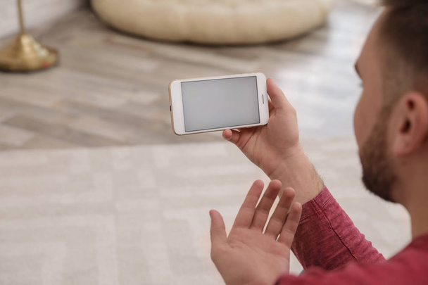 Mladý muž používá videokonverzaci na smartphone doma, v šatně. Prostor pro návrh - Fotografie, Obrázek