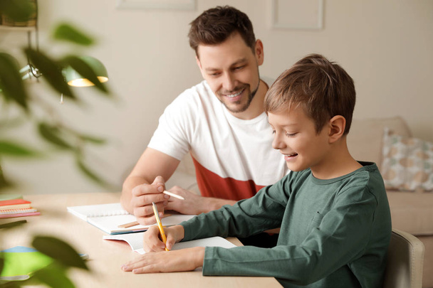 Dad helping his son with school assignment at home - Фото, зображення