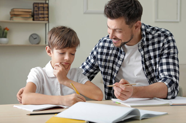 Dad helping his son with school assignment at home - Zdjęcie, obraz