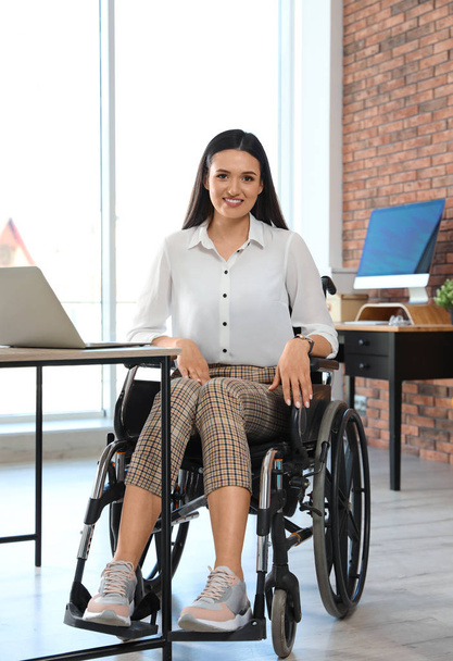 Portrait of young woman in wheelchair at workplace - Foto, immagini