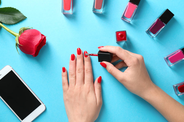 Woman applying bright nail polish on color background, top view - Fotoğraf, Görsel