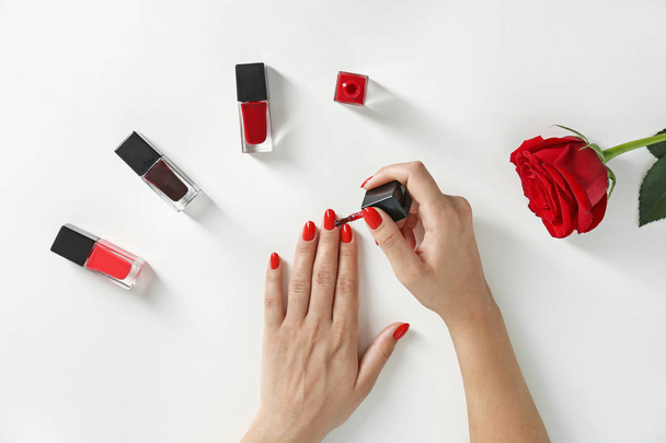 Woman applying bright nail polish on white background, top view - 写真・画像
