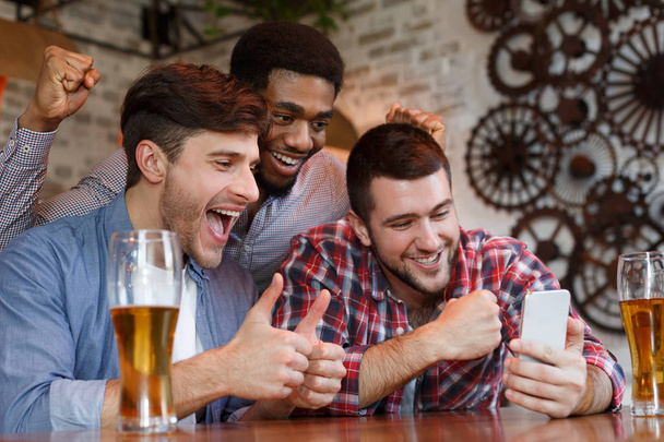Мужские друзья, имеющие видео-звонок на смартфоне в баре
 - Фото, изображение