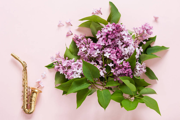 Little Golden saxophone and Bouquet of fresh fragrant pink lilac - Фото, изображение