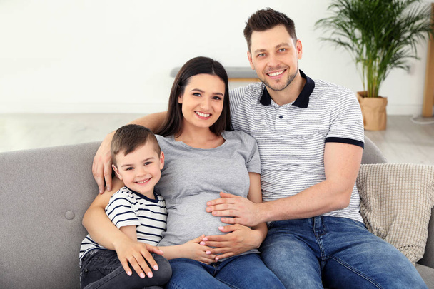 Padre, hijo y madre embarazada pasando tiempo juntos en el sofá en casa. Tiempo en familia
 - Foto, imagen