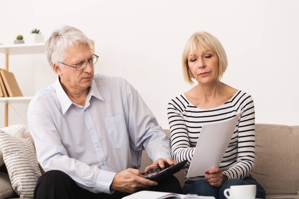 Беспокойные пожилые пары проверяют свои счета дома
 - Фото, изображение