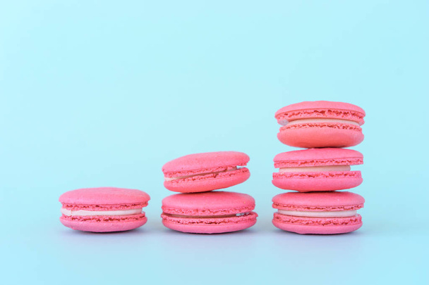 Pink macaroons on a blue background. Concepts of classification and growth. - Fotoğraf, Görsel