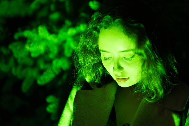 Portrait of a mysterious beautiful woman in green lighting with green background - Photo, Image