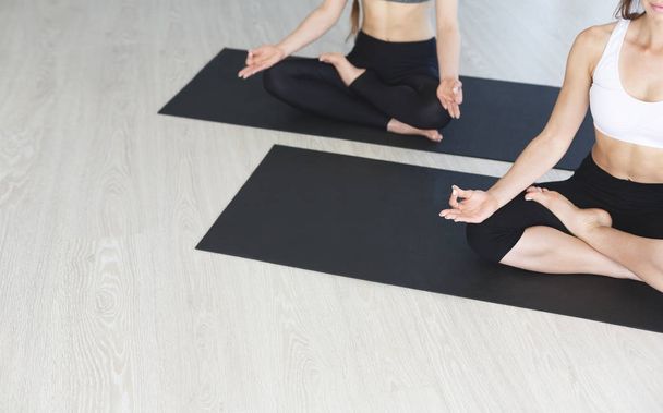 Mujeres jóvenes en clase de yoga haciendo ejercicios de meditación sobre esteras
 - Foto, imagen