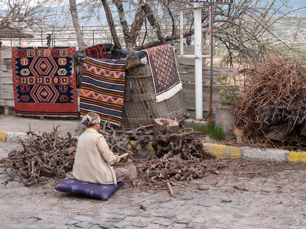 カッパドキアの旧市街の路上で木を切る女性 - 写真・画像