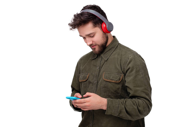 Φωτογραφία του όμορφου νεαρού άντρα που χρησιμοποιεί κινητά και ακούγοντας μουσική στα ακουστικά - Φωτογραφία, εικόνα