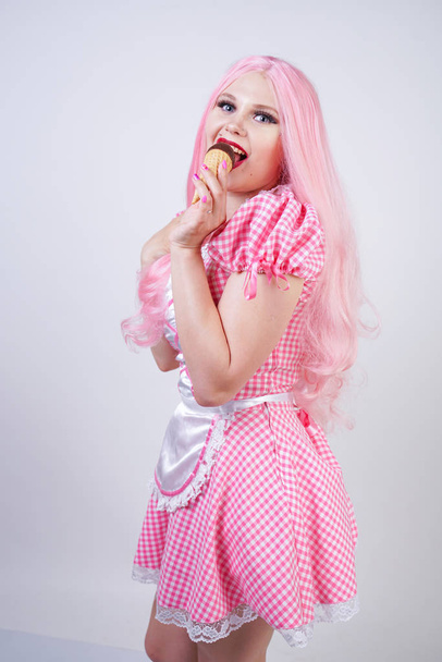 erotic caucasian chubby girl in pink plaid doll dress holds delicious summer ice cream and sexy flirts on white studio background - Photo, Image