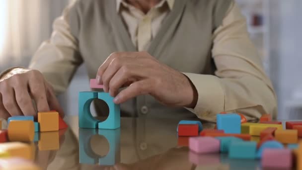 Elderly male making house colored wooden cubes, concentration exercise, therapy - Materiaali, video
