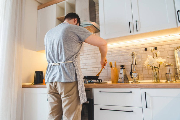 mies paistuu pannulla keittiössä. ruoanlaitto käsite
 - Valokuva, kuva