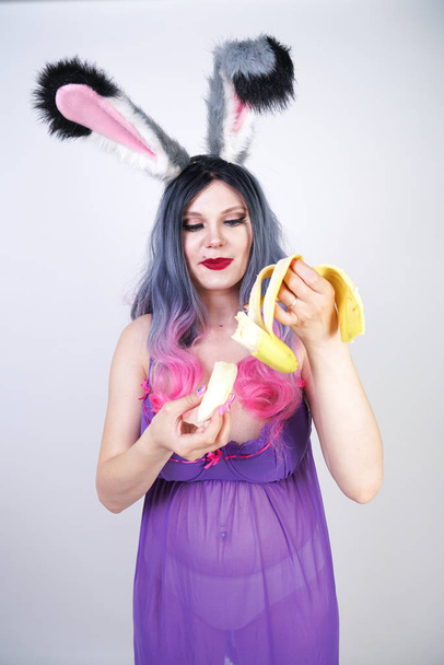 Kaukasisch mollig meisje in een transparante lingerie Babydoll jurk met konijn oren geniet en seksueel flirt op witte studio achtergrond - Foto, afbeelding