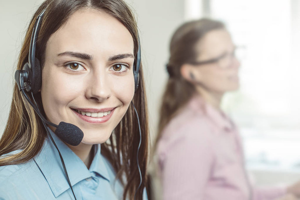 Retrato de una chica sonriente operadora del centro de llamadas. Amable joven agente en auriculares que trabajan en el servicio al cliente
.  - Foto, Imagen
