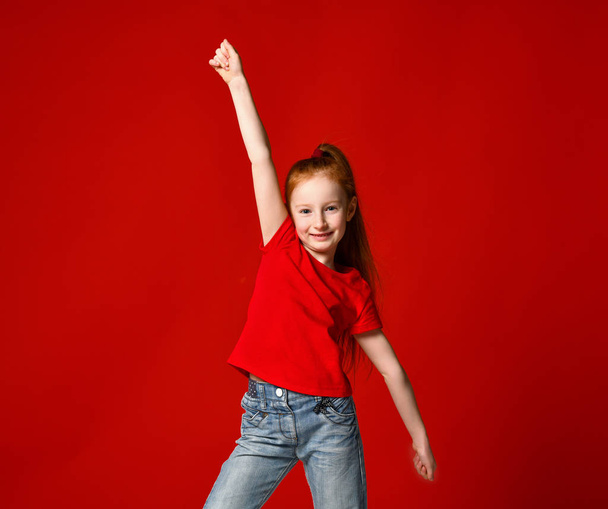Portrait of a young girl with red hair smiling at camera with hands in the air - 写真・画像
