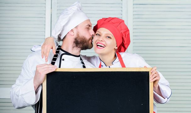 Man and woman chef cooking food together. Couple with blackboard for advertisement. Lovely family at kitchen. Family restaurant. Family day. Couple in love cooking together. Family values. Share joy - Fotoğraf, Görsel
