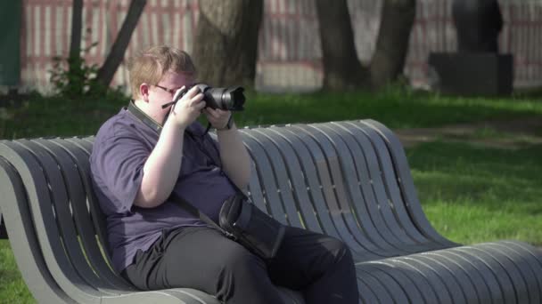 Młody człowiek robi zdjęcia w parku - Materiał filmowy, wideo