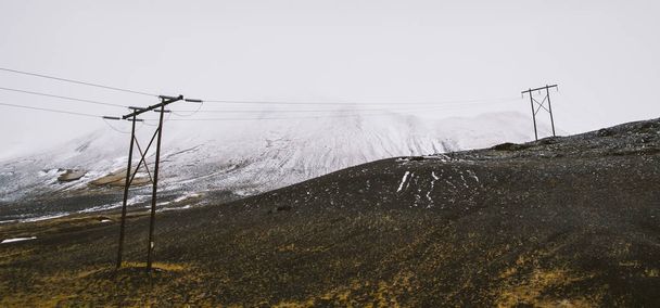 Postes de electricidad en medio de una montaña nevada para abastecer
 - Foto, Imagen