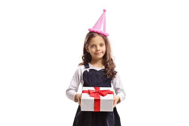 Cute little girl wearing a party hat and holding a present isolated on white background - Фото, зображення