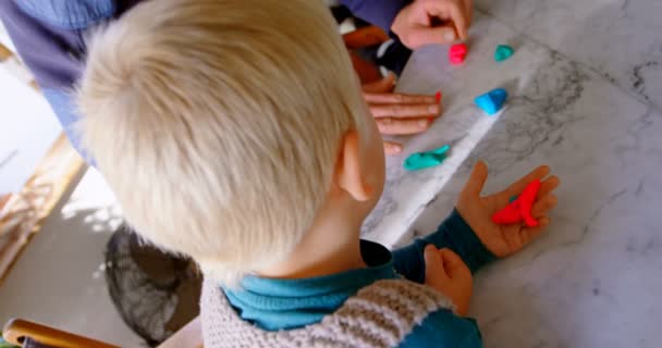 High angle view of Caucasian father and children playing together with clay in a comfortable home. They are sitting at table 4k - Filmati, video