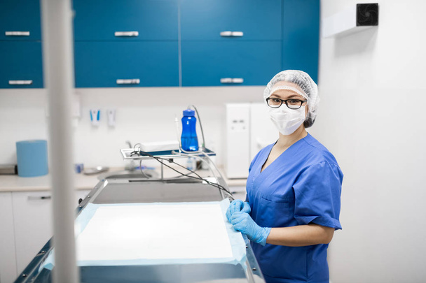 Vet wearing blue uniform and mask preparing for surgery - Photo, Image
