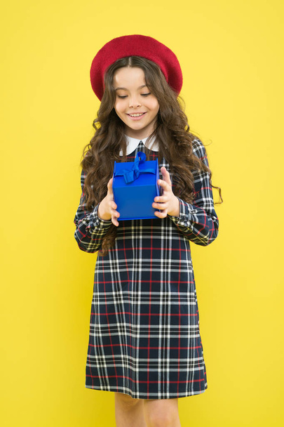 happy girl with long curly hair in beret. shopping. child with present box. parisian child on yellow background. happy birthday. . Holiday gift. small girl in french style hat. Time to shop - Photo, Image