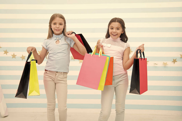 Girlish happiness. Kids happy carry bunch packages. Shopping with best friend concept. Girls like shopping. Kids happy small girls hold shopping bags. Enjoy shopping with best friend or sister - 写真・画像