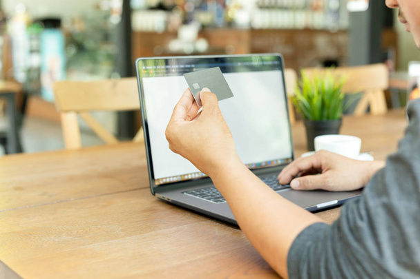 Бізнесмен онлайн робоча рука тримає кредитну картку і використовує ноутбук в кафе
. - Фото, зображення