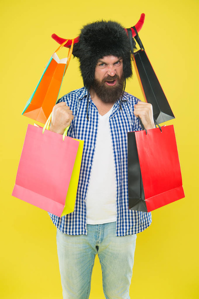 Sale prices are low, dont be slow. Happy hipster in bull horns hat holding shopping bags after seasonal sale. Bearded man smiling with purchases bought at sale. Black Friday and cyber monday sale - Foto, afbeelding