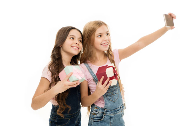 Like fashion models. Adorable little models have fun shooting self portrait photos. Happy small models holding smartphone on hand length and smiling to camera. Cute girl models taking selfie together - Foto, Imagen