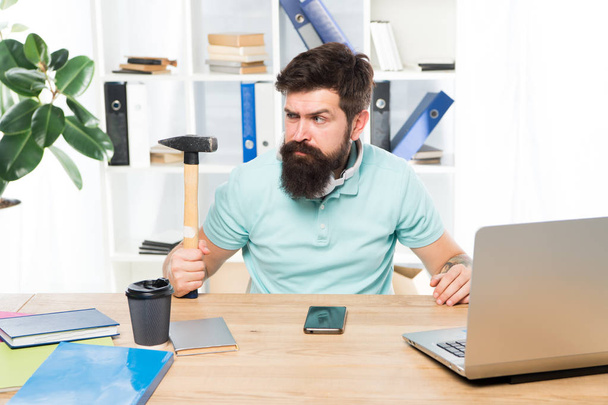 Office life makes him crazy. Businessman with beard and mustache gone mad with hammer in a hand. Angry aggressive businessman in office. Frustrated office worker holding hammer poised ready to smash - Foto, afbeelding