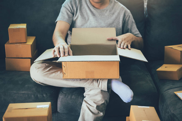 Asian entrepreneur teenager is opening a cardboard box in order  - Φωτογραφία, εικόνα