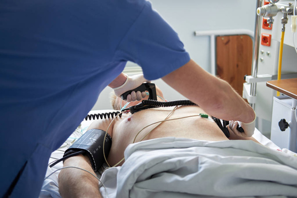 Интенсивный врач проводит дефибрилляцию критически важного пациента
 - Фото, изображение