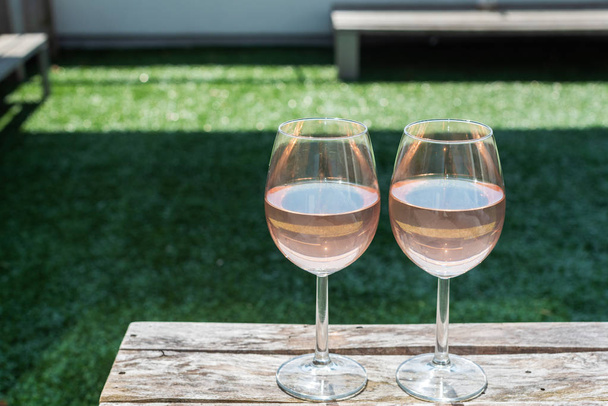 Tahta bir masada iki bardak gül şarabı - Fotoğraf, Görsel