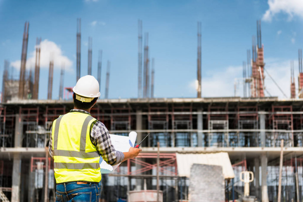 Engineering Consulting People on construction site holding blueprint in his hand. Building  inspector. Construction site check drawing and business workflow of new building - Foto, imagen