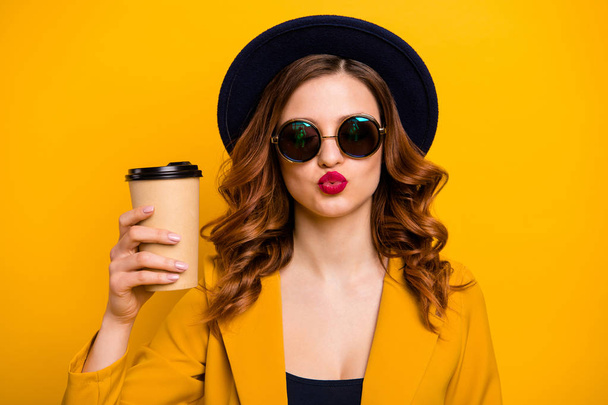 Close up photo beautiful funky dreamy she her lady send air kiss flirty vacation hot beverage takeout paper container hand arm wear specs formal-wear suit isolated yellow bright background - Фото, изображение