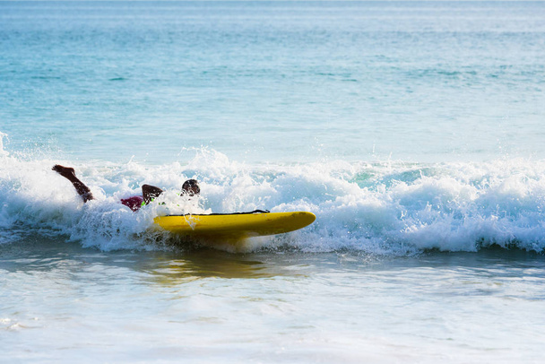 Asian młody człowiek jazda fala lub surfing na plaża., outdoor aktywny styl życia w lecie. - Zdjęcie, obraz